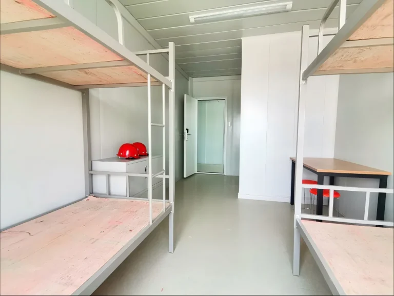 KUBO dormitory reference interior with bunk frames, central aisle and rear partition