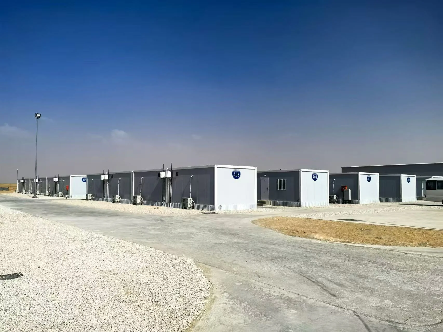 Rows of modular workforce accommodation buildings beside controlled roads and site lighting