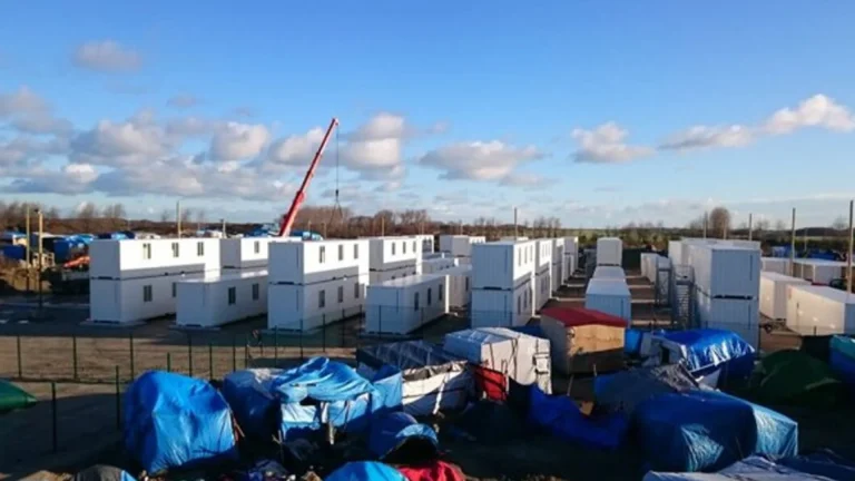 Modular camp buildings being assembled with lifting equipment and staged materials