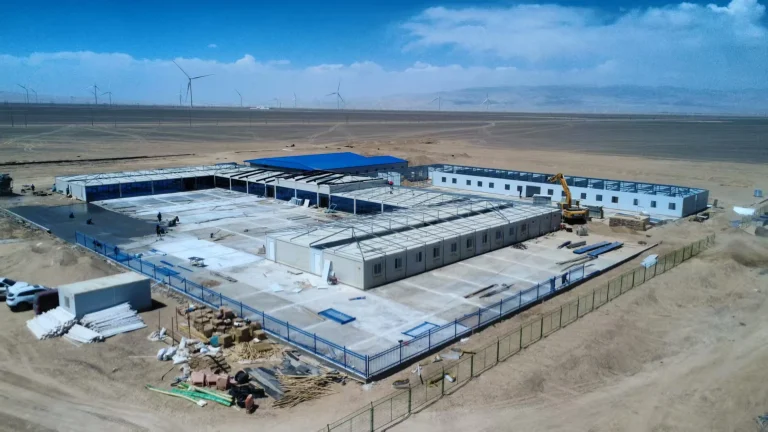 Modular camp buildings during phased roof installation near wind turbines