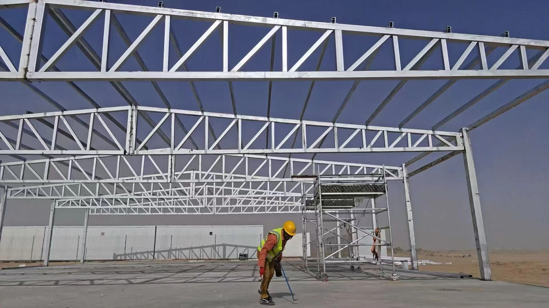Worker installing steel roof trusses for a modular project building