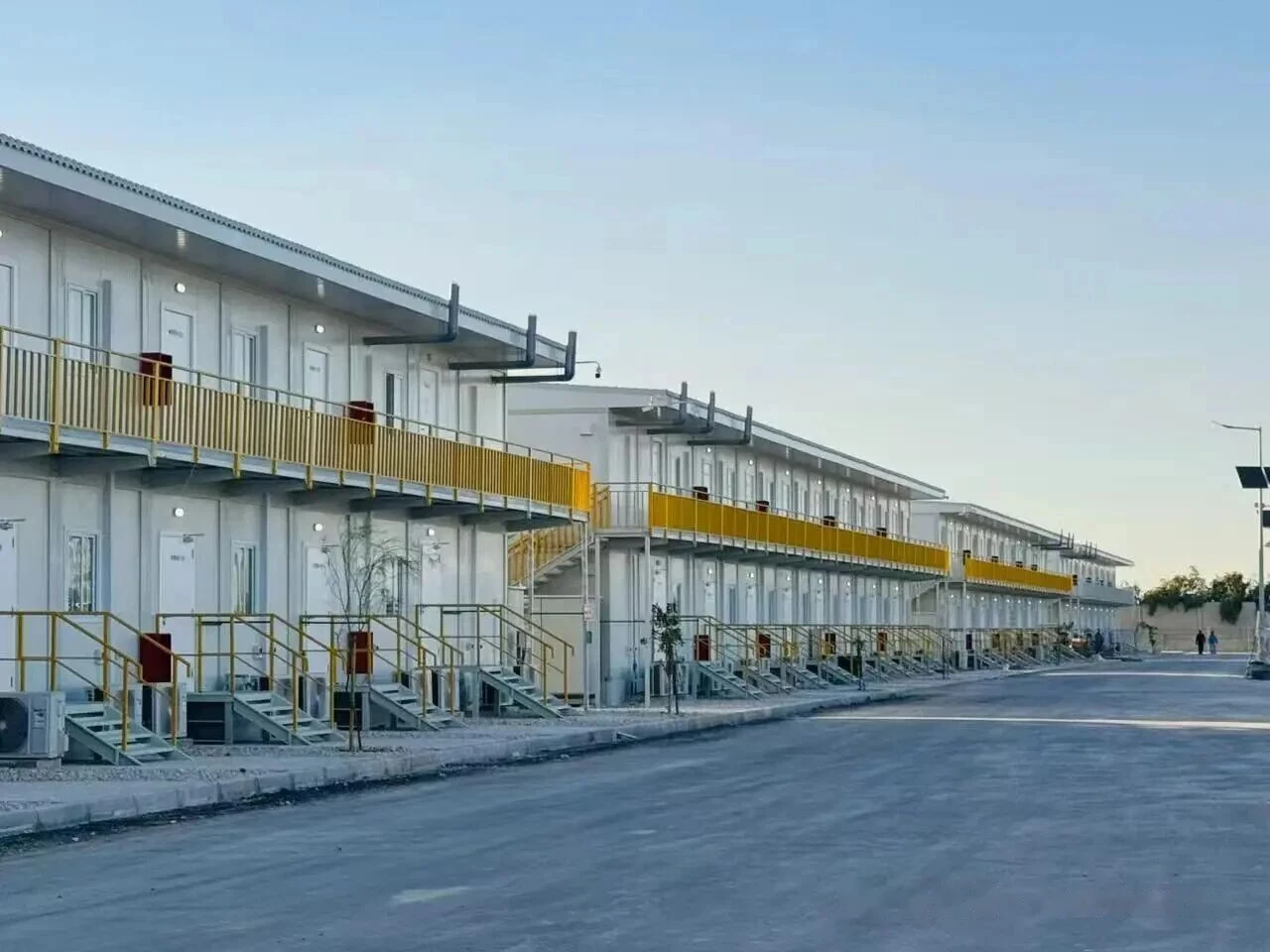 Rows of multi-story modular dormitory buildings at dusk in a purpose-built workforce village