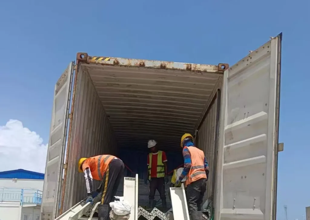 Crew unloading KUBO modular building components from a freight container at a project site