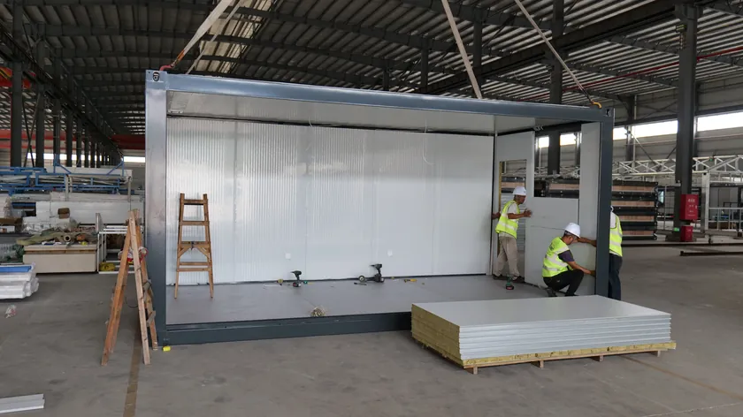 Workers fitting wall panels inside a modular building frame