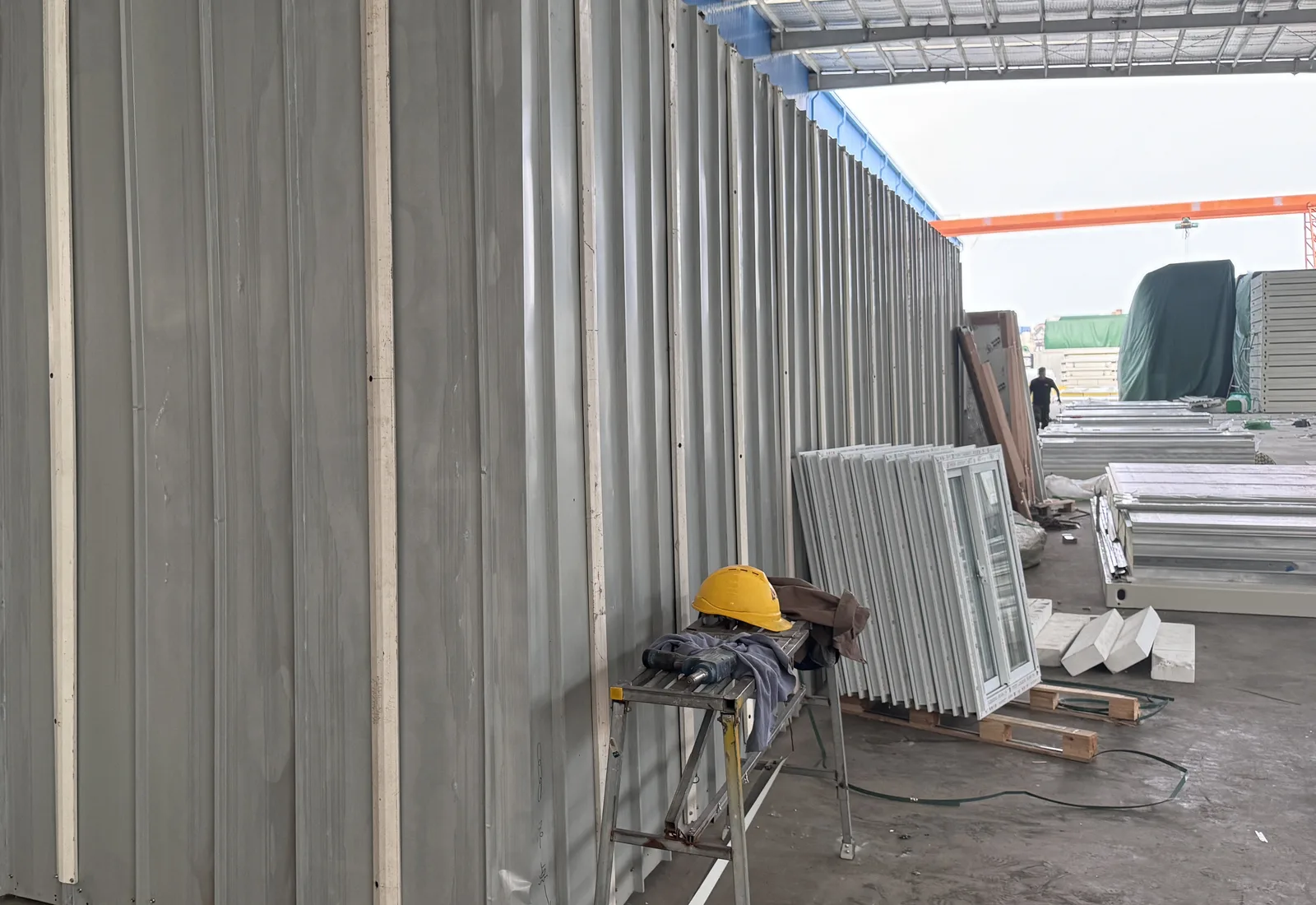 Wall panels, window frames and flat steel packages staged by component in a factory