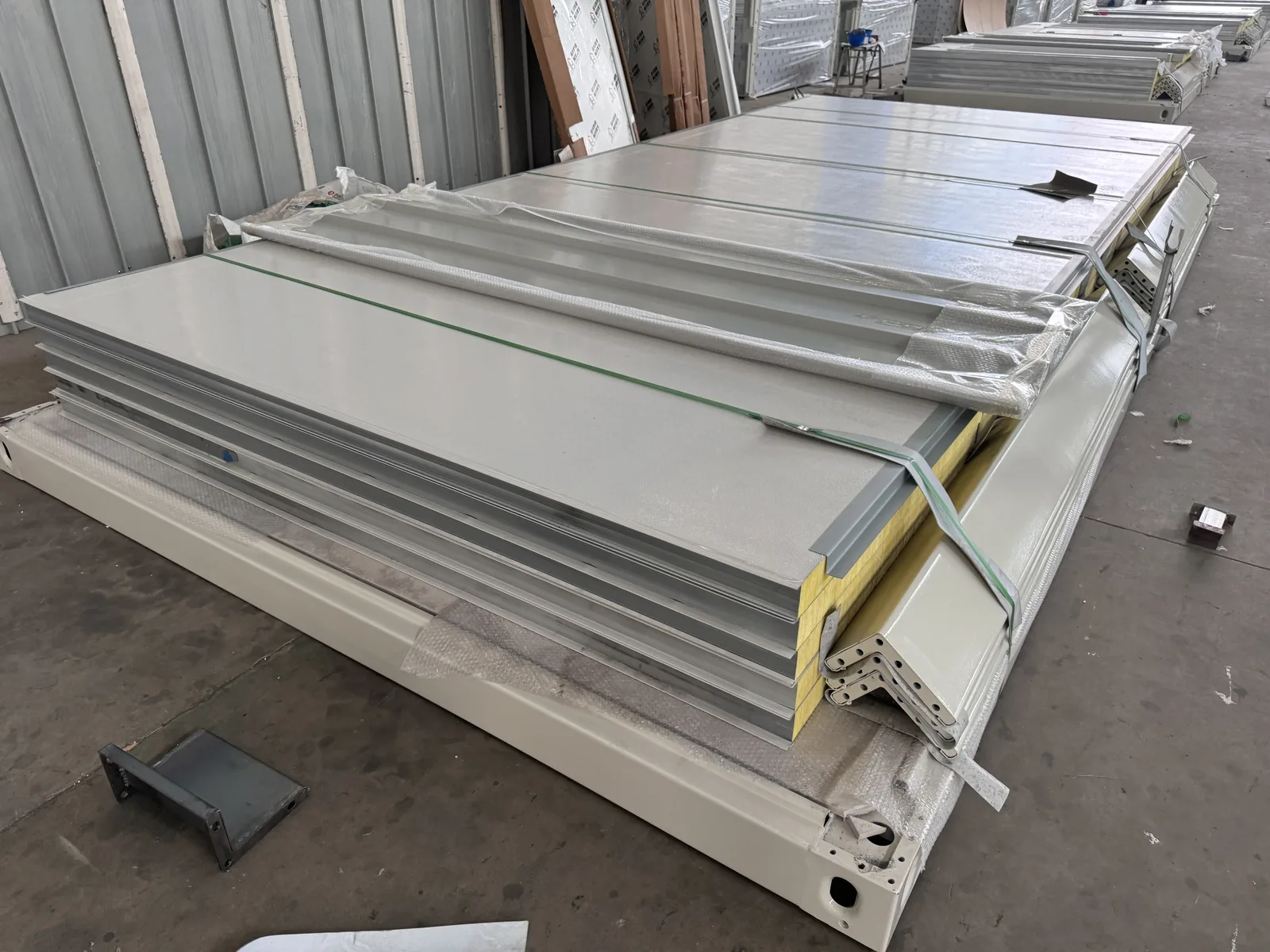 Strapped wall panels and steel components with protective wrapping in a KUBO factory