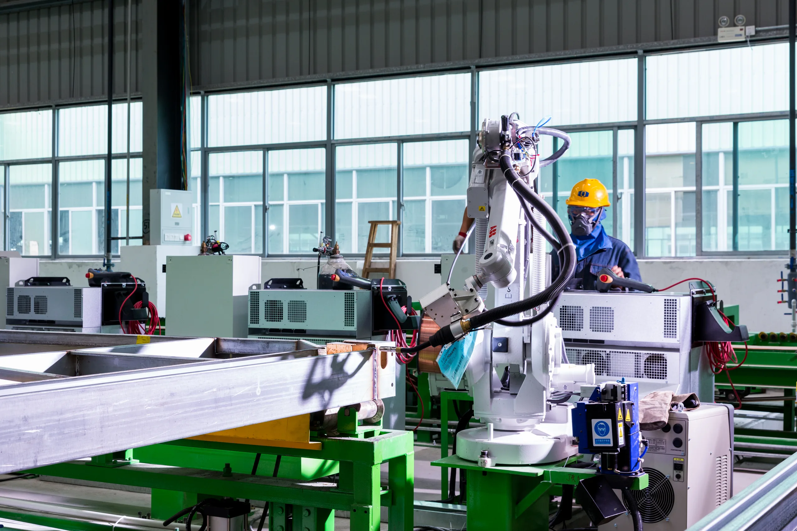 KUBO technician operating a robotic welding cell during modular frame production
