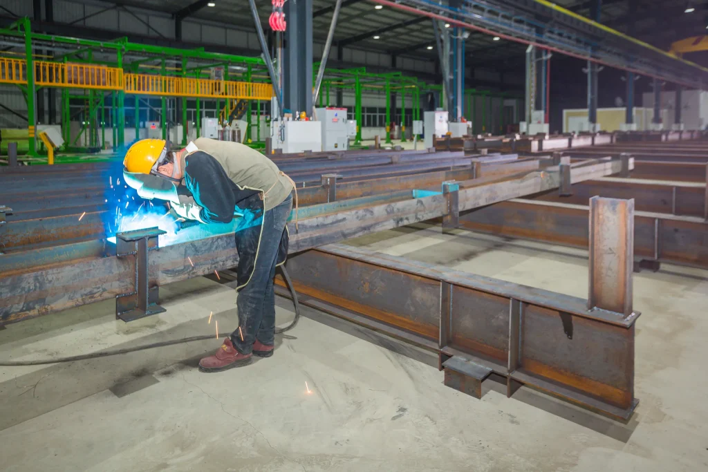 Worker welding a modular building steel frame on the KUBO factory production line